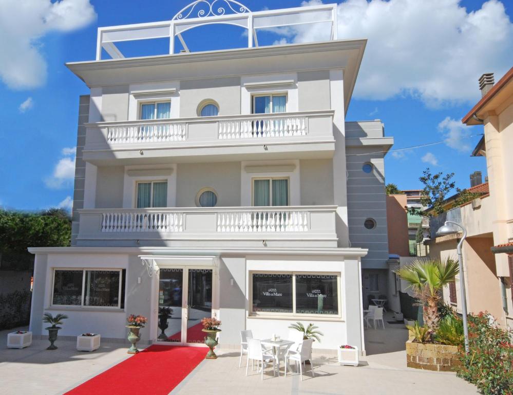 里米尼Hotel Residence Villa Del Mare的带阳台的白色建筑和红地毯