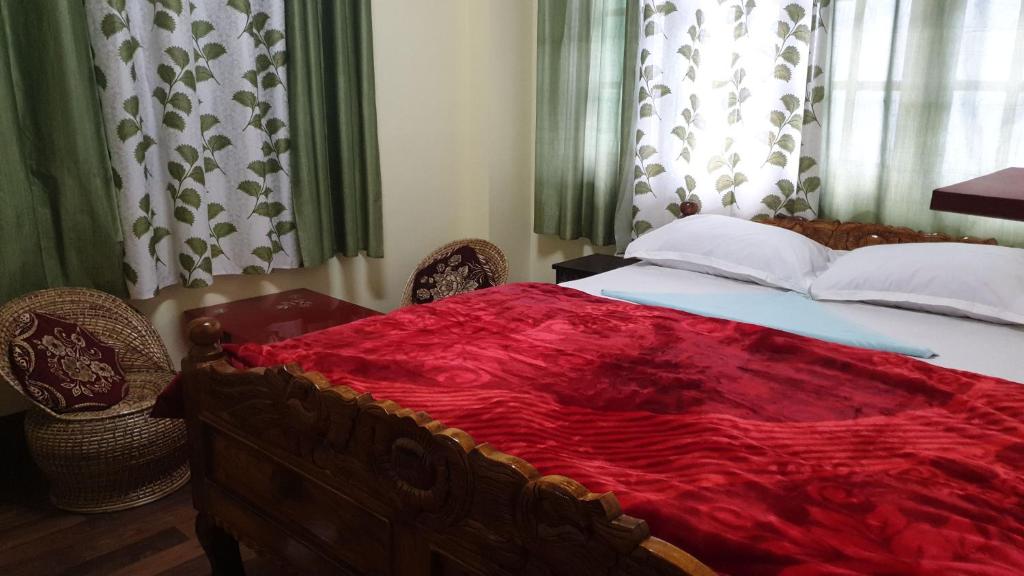 大吉岭Mahakal homestay的一间卧室配有一张床铺,床上铺有红色毯子