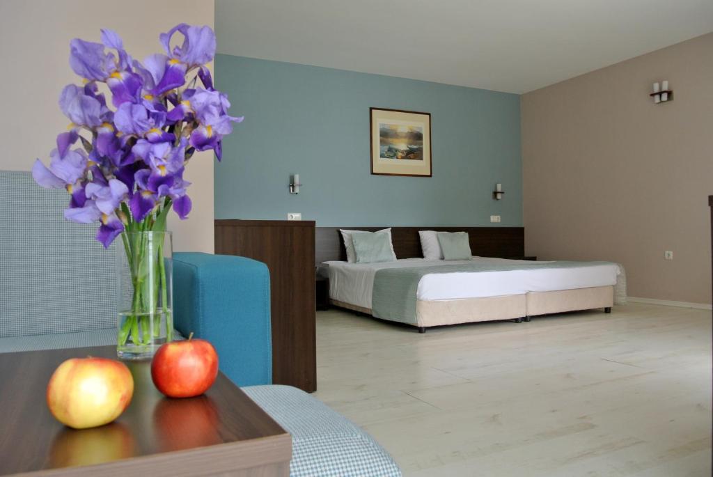 巴尔奇克Valeo Hotel的一间卧室,配有一张床和紫色花瓶