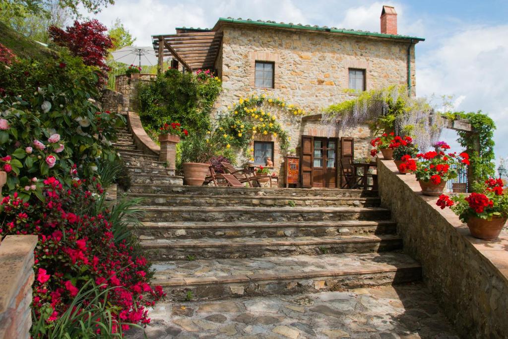 切奇纳谷新堡Podere Piandicava的一座古老的石头房子,有楼梯和鲜花