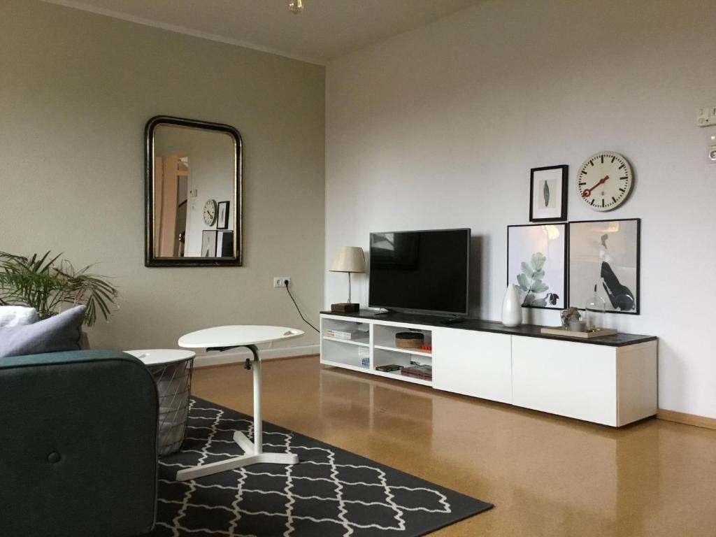 多斯滕Wohlfühlambiente in Dorsten的客厅配有电视、桌子和镜子