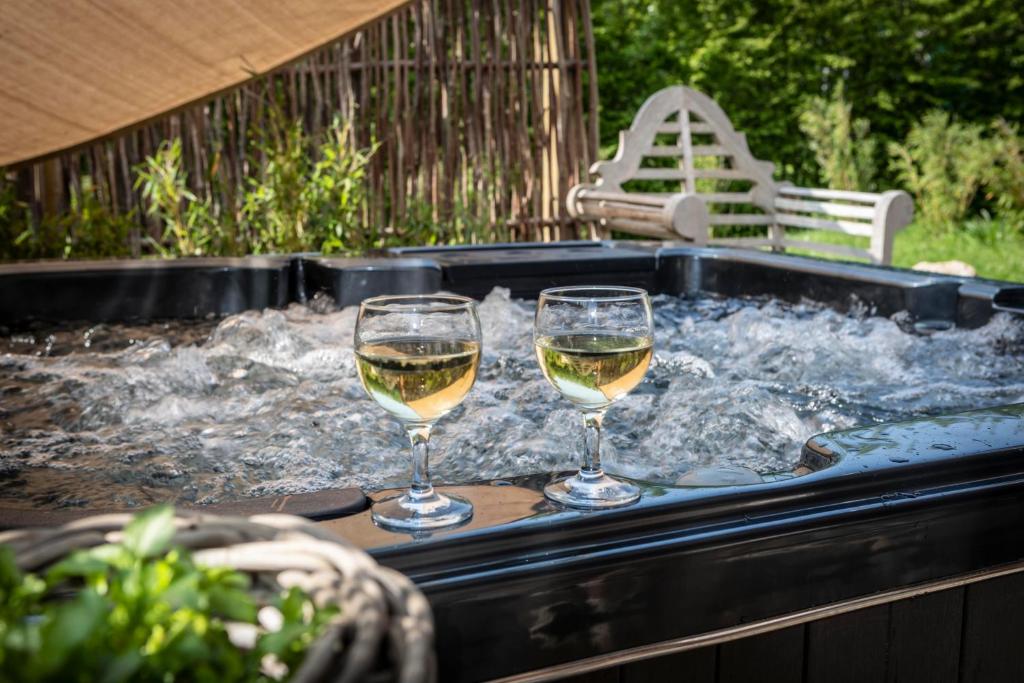 韦尔维耶Du Coté de chez Jeanne, Suite的热水浴池内的2杯葡萄酒和水