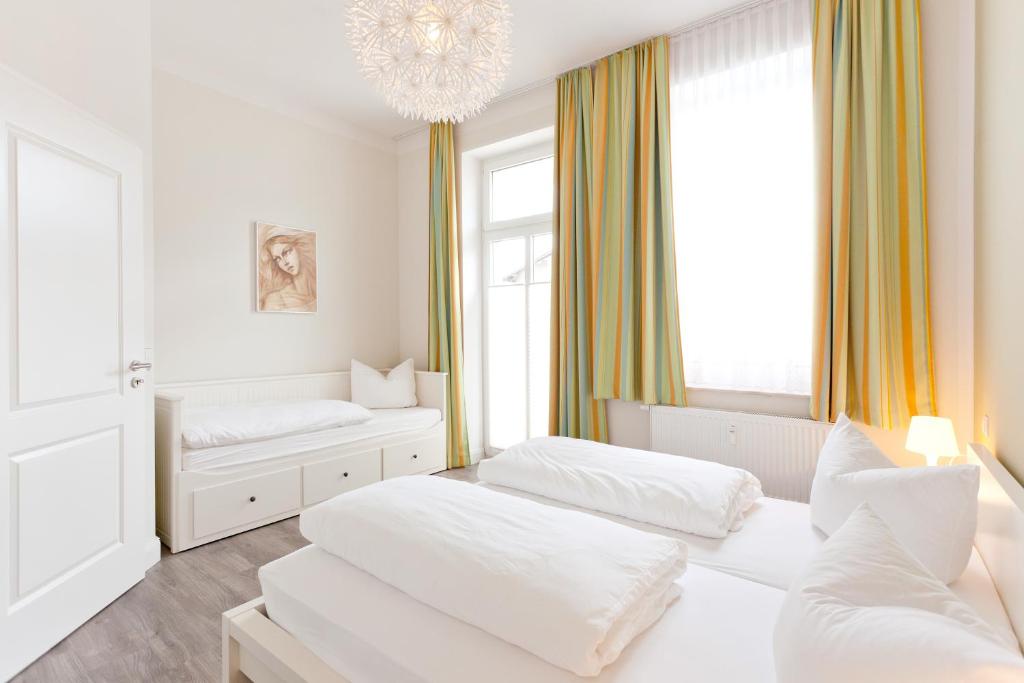 宾茨Ferienwohnungen Familie Glasner的白色的客房设有两张床和吊灯。