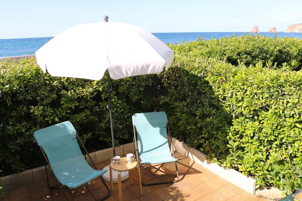 昂代Hendaye Beach Studio, front de mer avec parking privé的两张椅子和一张带雨伞的桌子