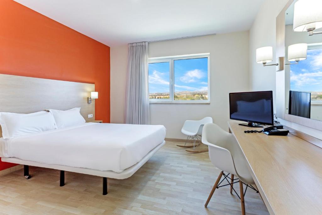 拉斯·罗萨斯·德·马德里B&B HOTEL Madrid Las Rozas的酒店客房配有一张床和一张带电脑的书桌
