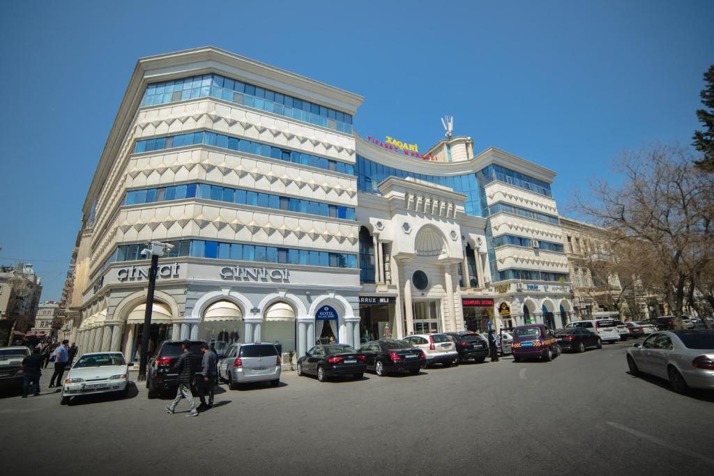 巴库Salam Baku Hotel (SBH)的一座大型建筑,前面有汽车停放