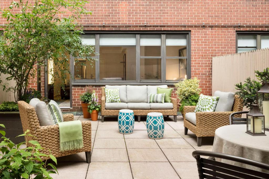 纽约The Gardens Sonesta ES Suites New York的庭院设有藤椅和沙发