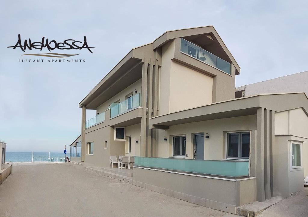 斯卡拉伯塔麦斯Anemoessa Elegant Apartments的海滩上的建筑,以海洋为背景