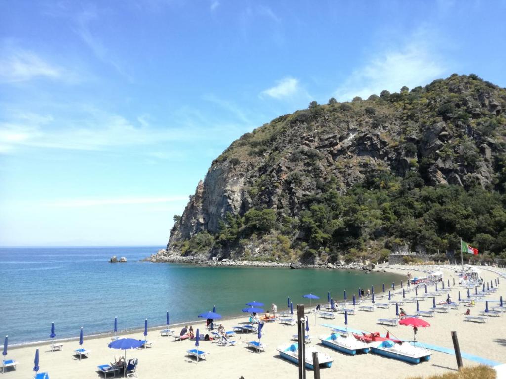 伊斯基亚Villetta Baia San Montano的海滩上设有椅子和遮阳伞,还有大海
