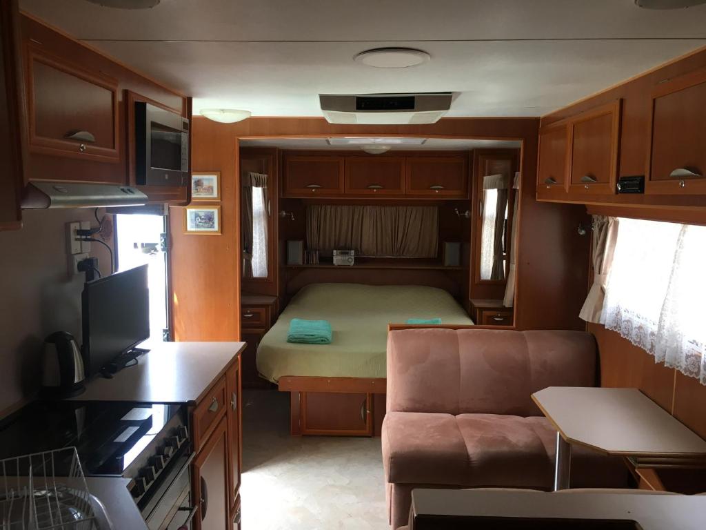 库克敦Comfortable caravan的小房间设有床和沙发以及厨房