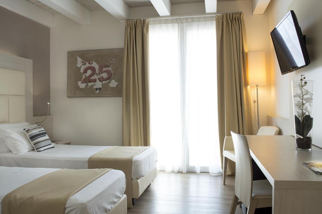 梅斯特亚历山大酒店 的酒店客房设有两张床、一张桌子和一台电视。