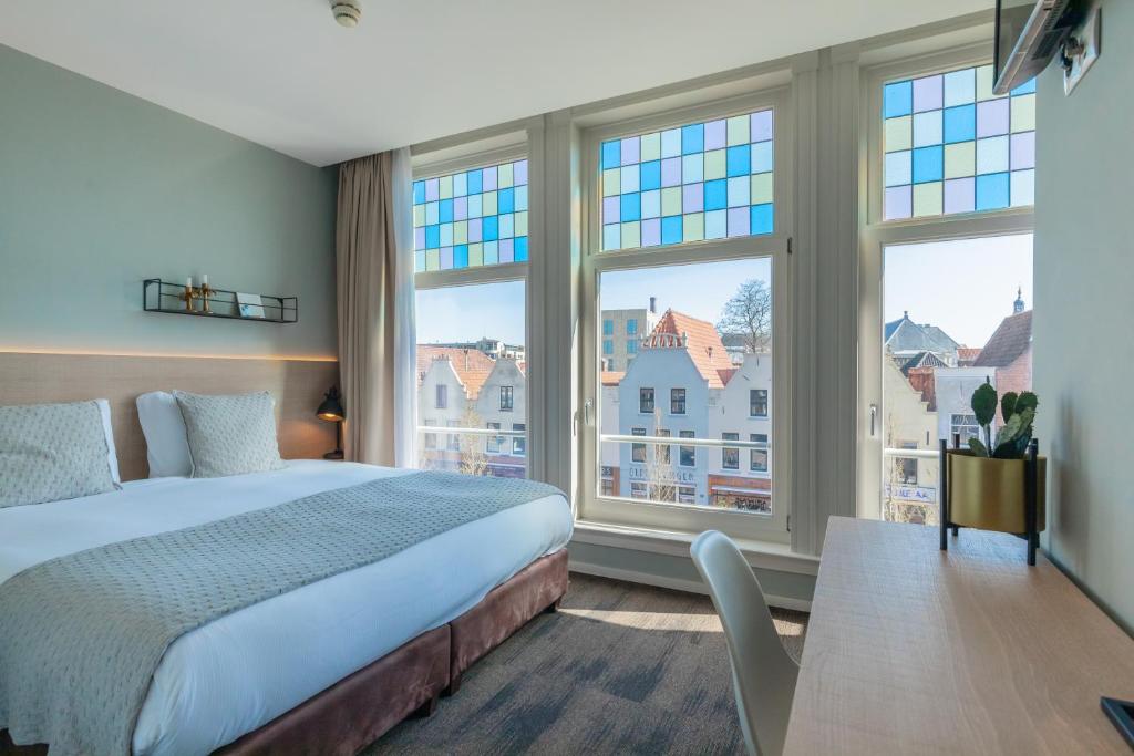 莱顿City Hotel Rembrandt的一间卧室设有一张床和两个大窗户