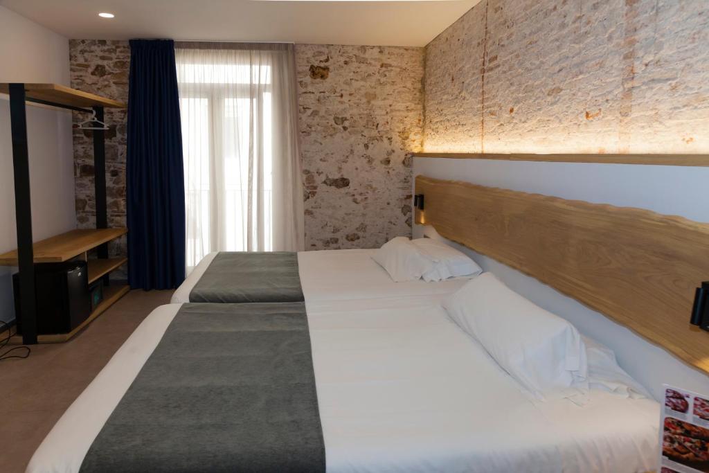 巴塞罗那巴黎旅馆的一间卧室设有两张床和砖墙