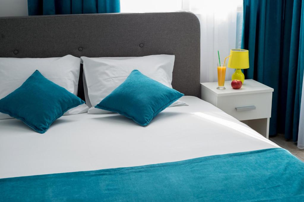 赫尔采格诺维Apartments Sunrise的一张带蓝色枕头的白色床和床头柜