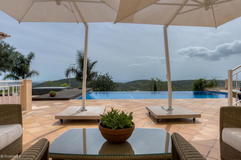 楼尔卡萨莫秋布兰科酒店的一个带桌子和遮阳伞的庭院和一个游泳池