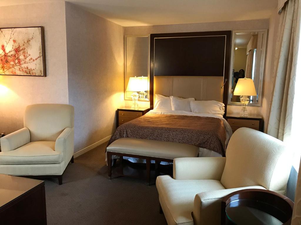 圣托马斯红衣主教苑汽车旅馆的酒店客房,配有一张床和两把椅子