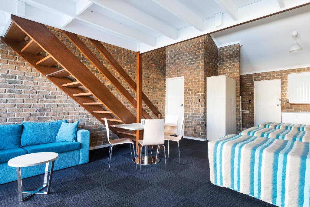 阿德莱德马里昂汽车旅馆及公寓的一间设有蓝色沙发、桌子和椅子的客房