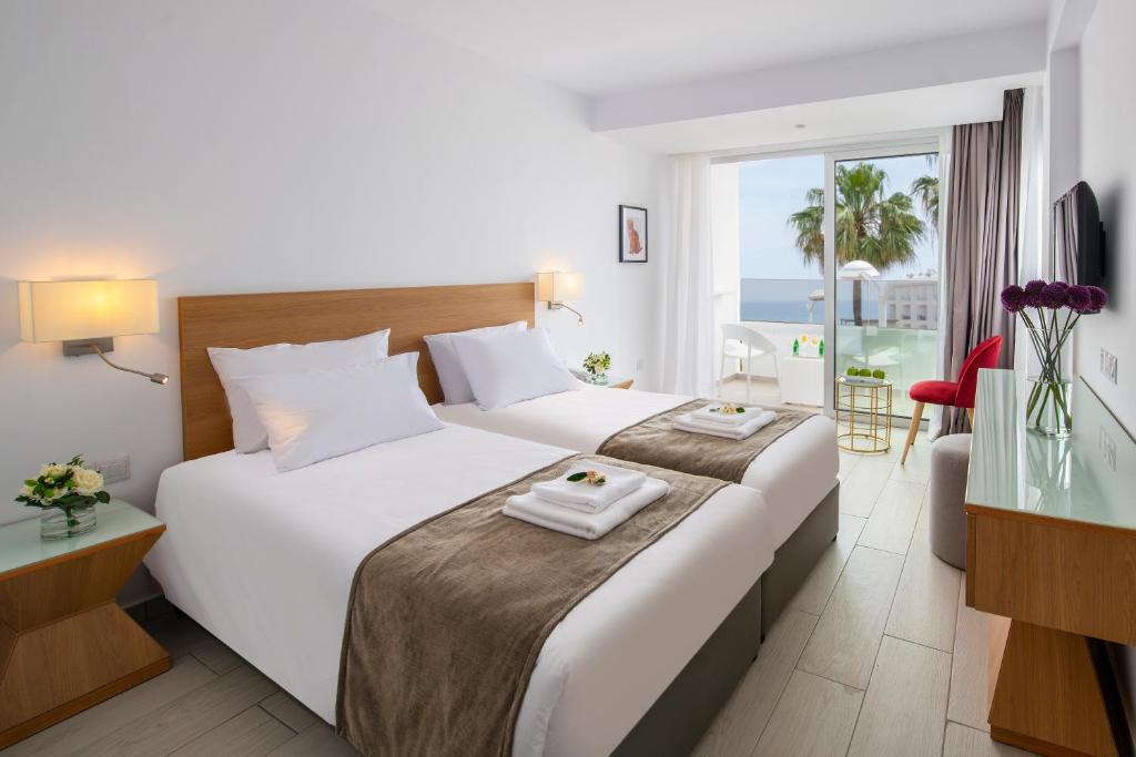 普罗塔拉斯Kokkinos Boutique Hotel的酒店客房设有两张床,享有海景。