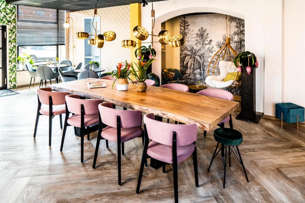 韦斯特卡佩勒Boutique Hotel Charley's的用餐室配有木桌和粉红色椅子