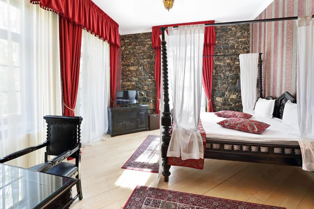 锡纳亚Regal 1880的一间卧室配有天蓬床和红色窗帘