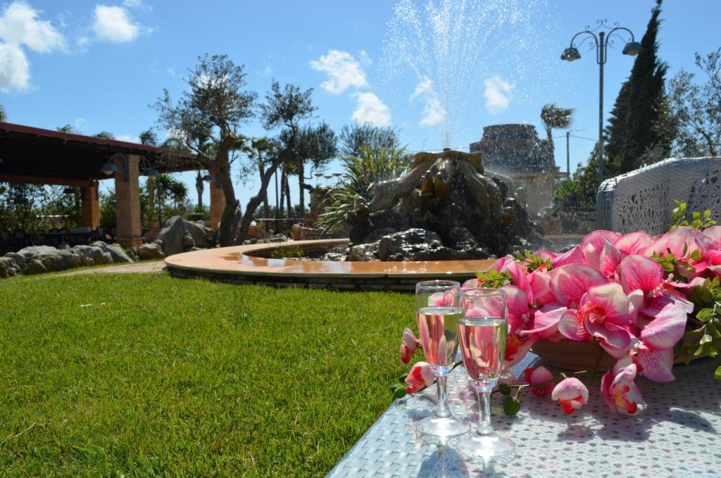 陶里萨诺Masseria Grande的一张桌子,上面放着酒杯和粉红色的鲜花