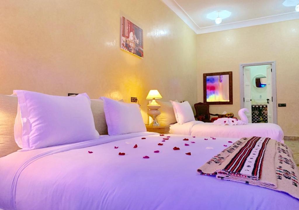 马拉喀什KOUTOBIA ROYAL的床铺上的玫瑰花酒店客房内的两张床