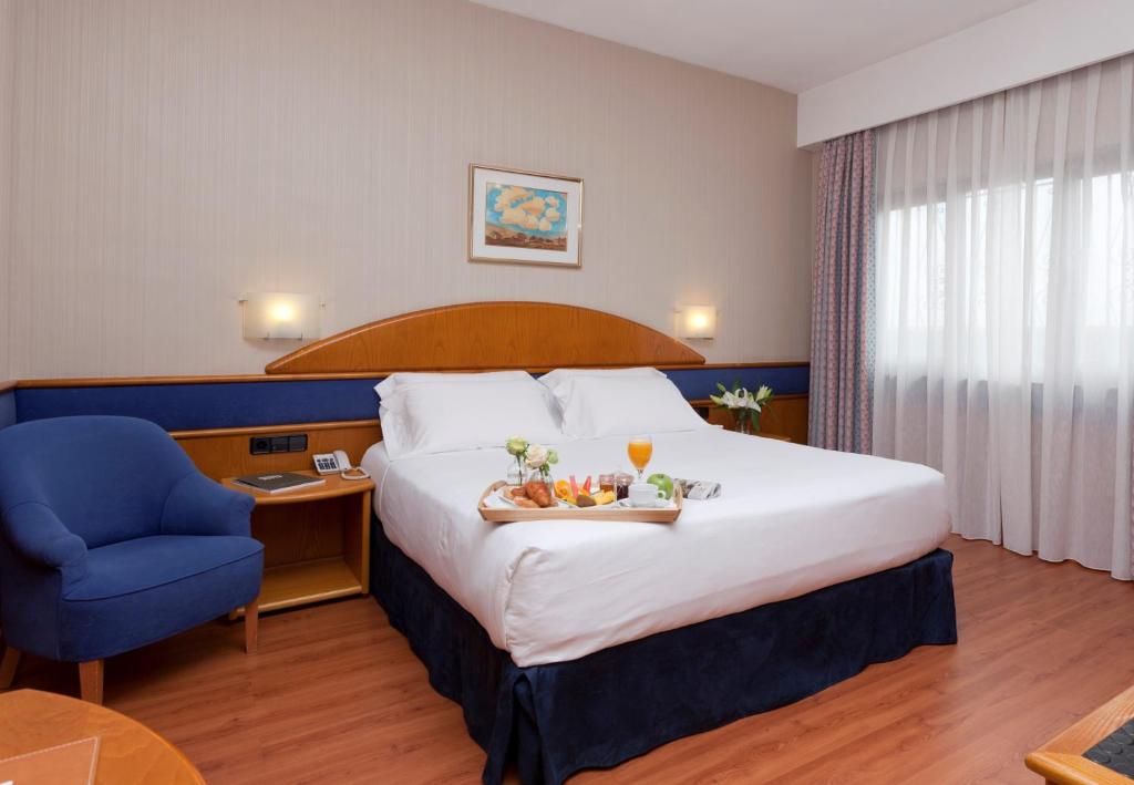 马德里阿古玛酒店的酒店客房带大床和蓝椅