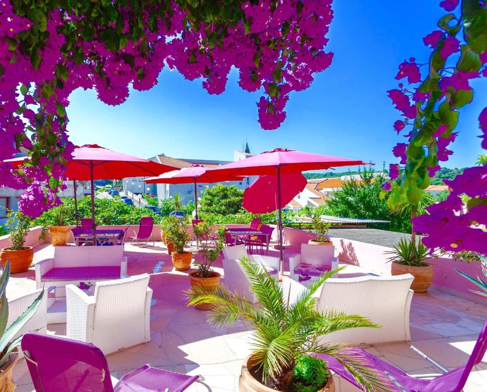 马卡尔斯卡Luxury Apartments Marhella & Jakov的一个带红色遮阳伞、椅子和植物的庭院