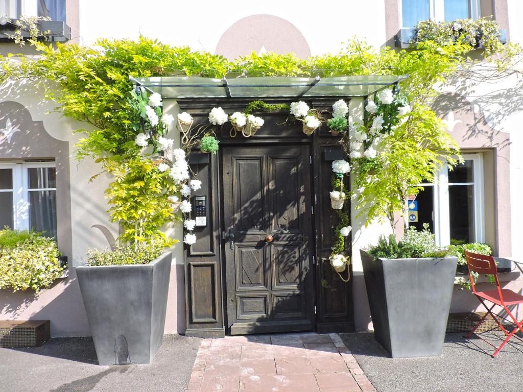 HabsheimLes Chambres de Louise的一座带鲜花的黑色门的建筑的入口