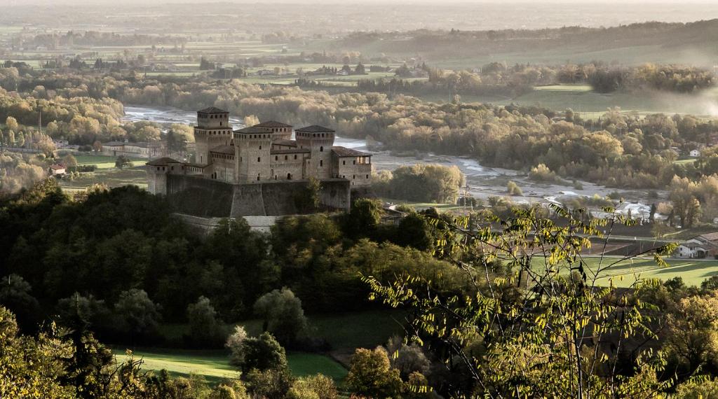 Torrechiara罗坎达德尔博尔戈酒店的一座树冠茂密的山顶上的城堡