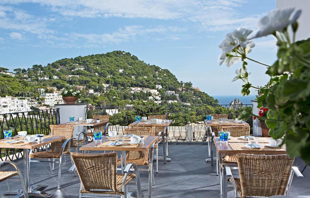 卡普里Hotel La Tosca的一个带桌椅的庭院和山脉
