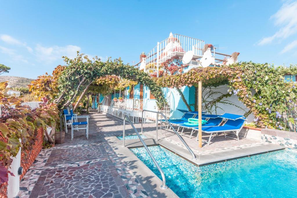 伊斯基亚Hotel Casa Giuseppina的一个带椅子和遮阳伞的游泳池的度假酒店
