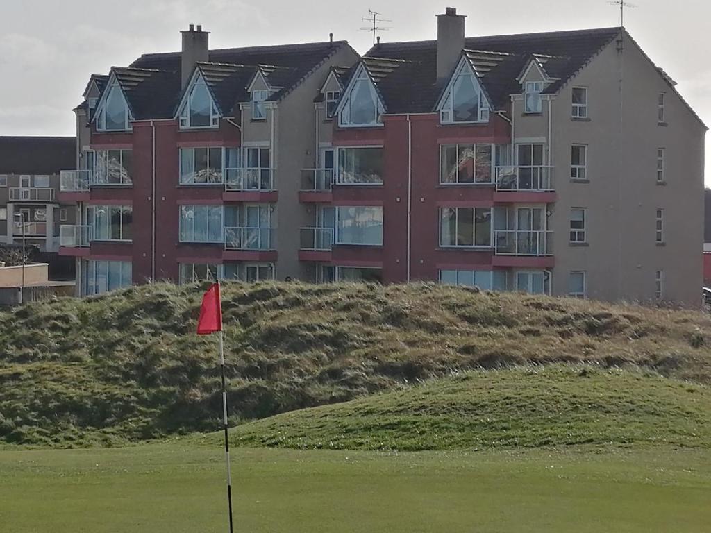 波特拉什Links Vista Portrush的一座在高尔夫球场上悬挂红旗的大建筑