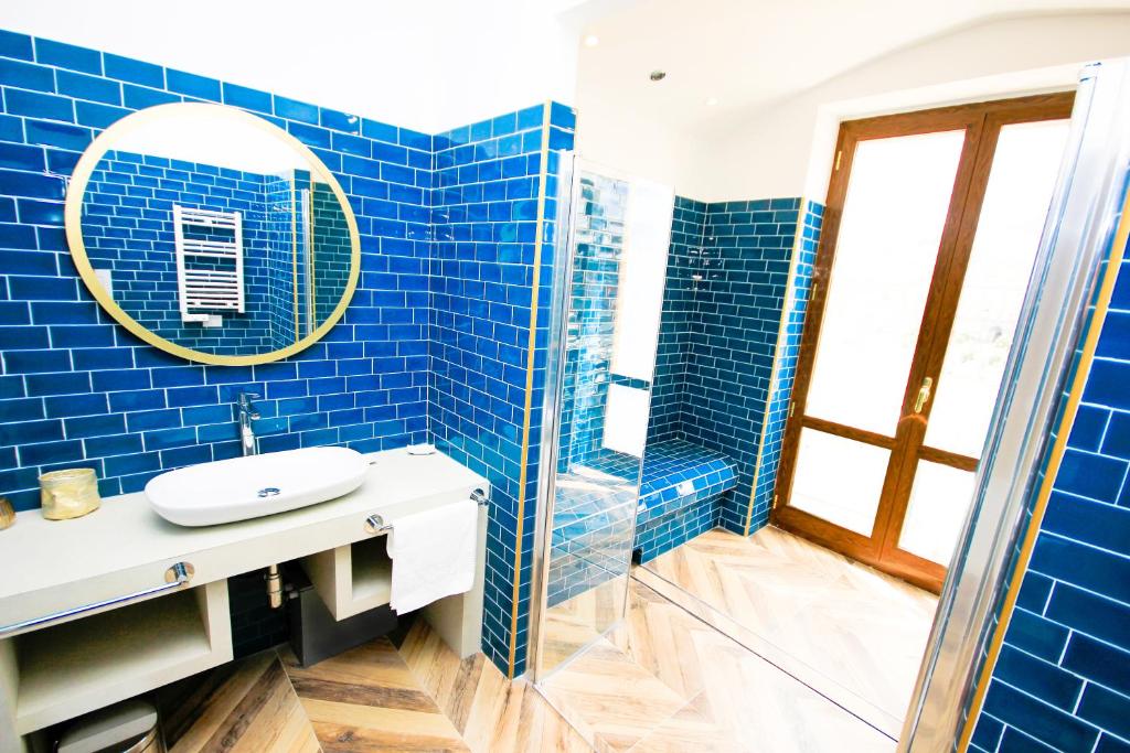 那不勒斯Don Raffaele Resort的蓝色瓷砖浴室设有水槽和镜子
