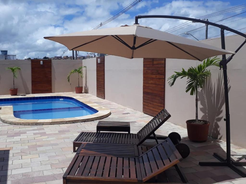 卡鲁阿鲁Hotel Itaparica的一个带遮阳伞和椅子的庭院和一个游泳池