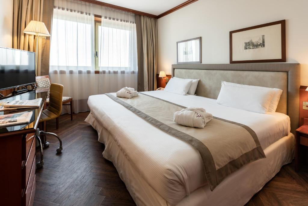 圣马尔蒂诺博纳尔贝尔戈Hotel Catullo的酒店客房设有一张大床和一台电视。