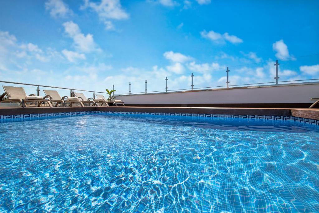 马拉加萨勒马拉加中央酒店的一个带椅子和蓝天的大型游泳池
