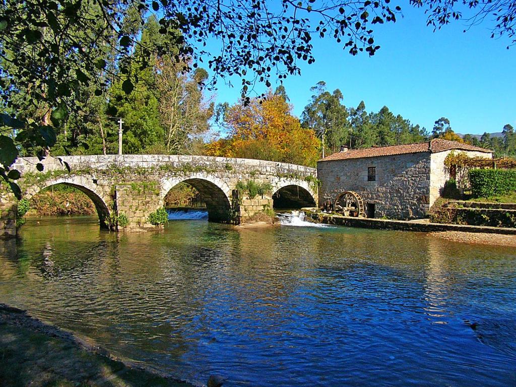 蓬德利马Moinho de Estoraos的一座石桥,在一座建筑物旁的一条河流上