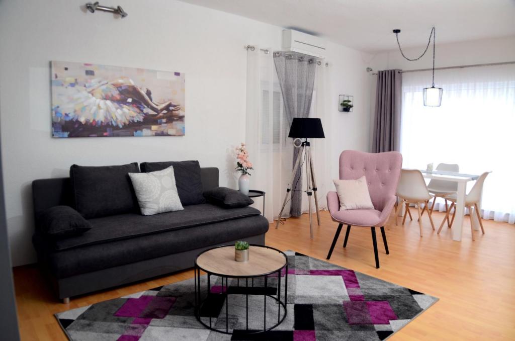 扎达尔Apartments La Luna的客厅配有黑色沙发和粉红色椅子