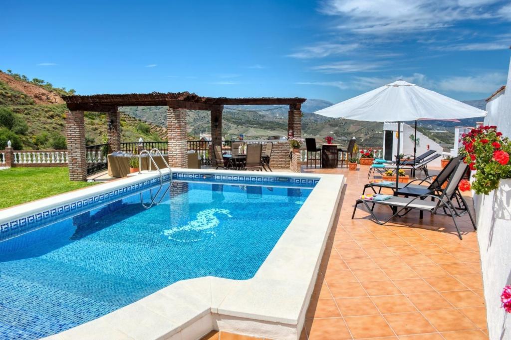 IznateCasa las Torres B&B的一个带桌椅和遮阳伞的游泳池