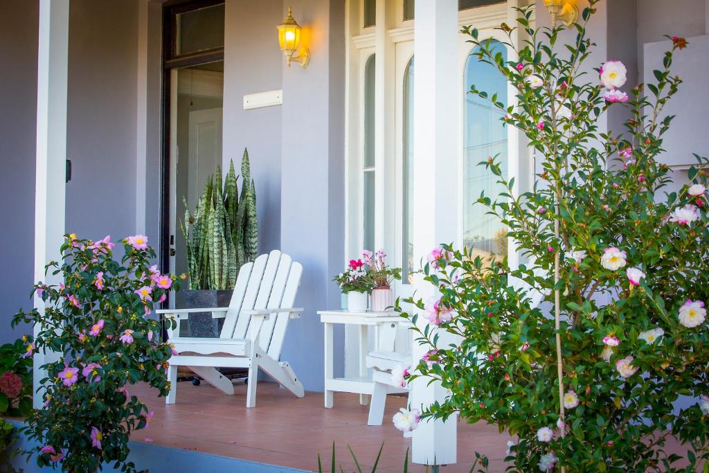塞斯诺克Camellia Cottage的一个带鲜花和白色椅子的门廊
