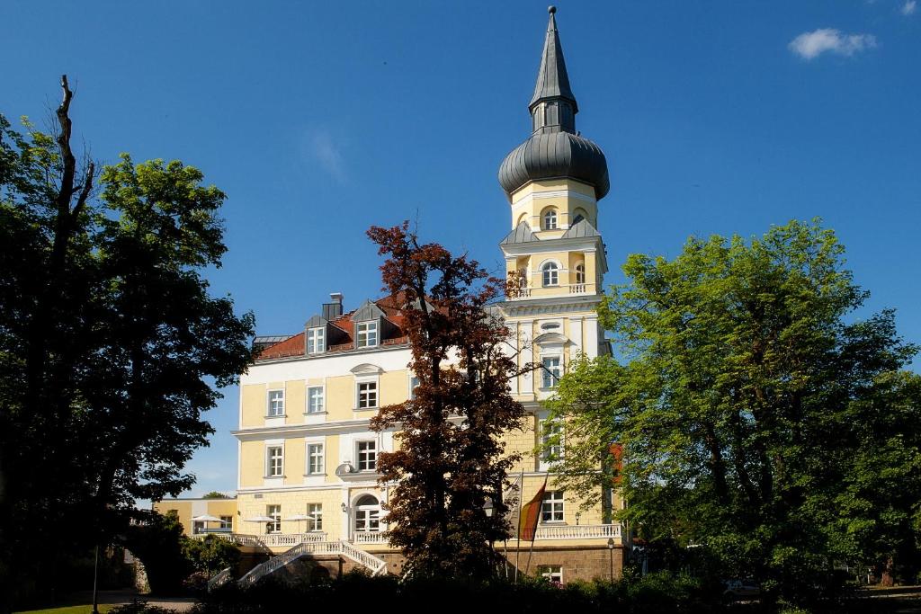 施瓦岑费尔德施彻沃赞菲尔德施洛斯酒店的一座高大的白色建筑,有钟楼