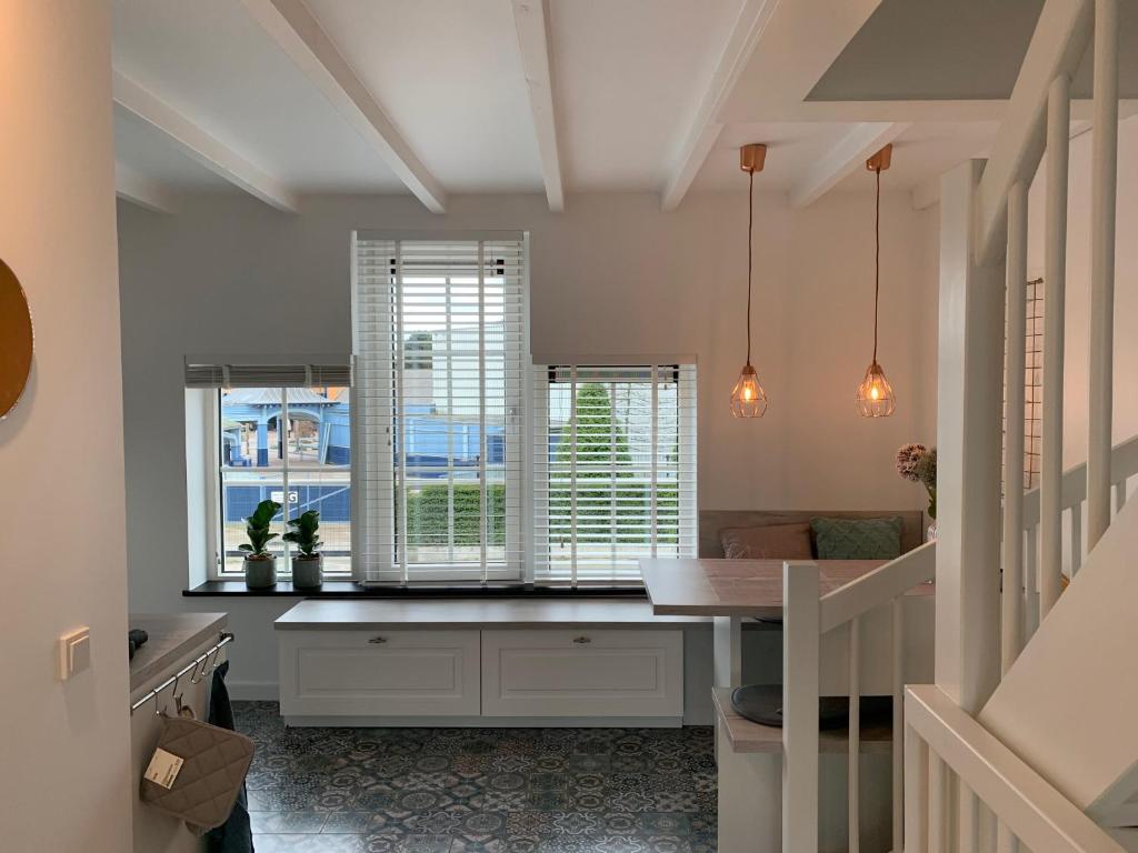 哈尔德韦克Boothuis Harderwijk的厨房配有桌子、两个窗户和柜台