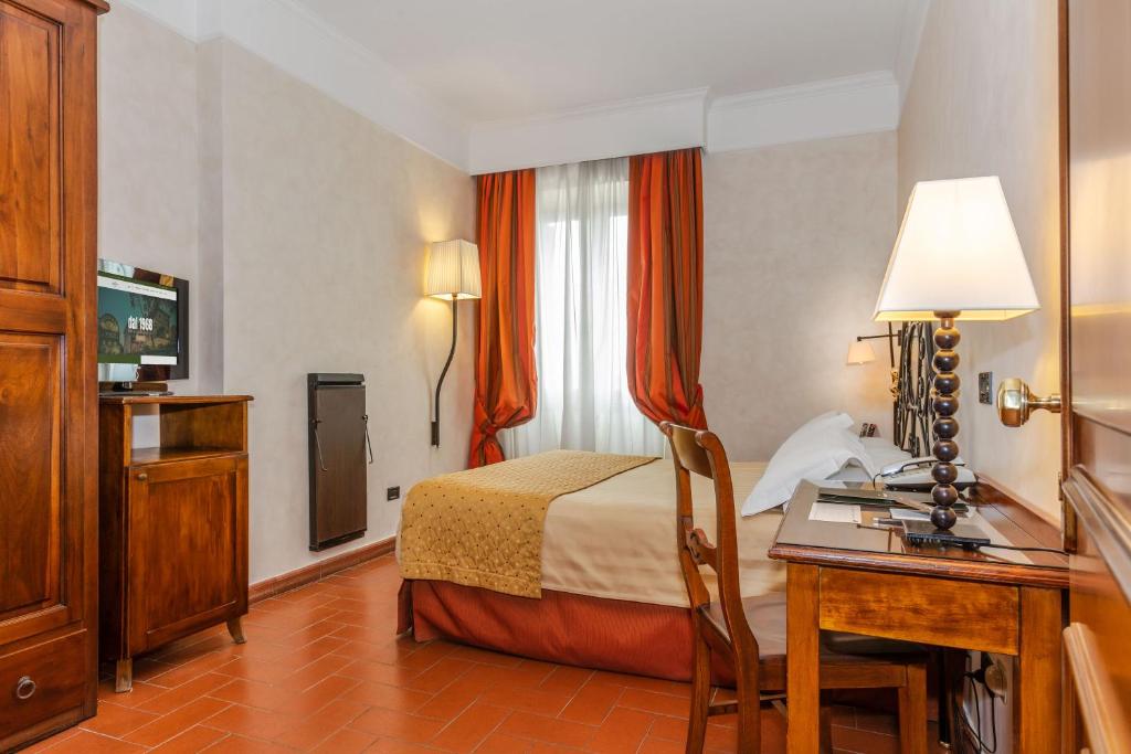 马利亚诺萨比纳Hotel Ristorante La Pergola的配有一张床和一张书桌的酒店客房