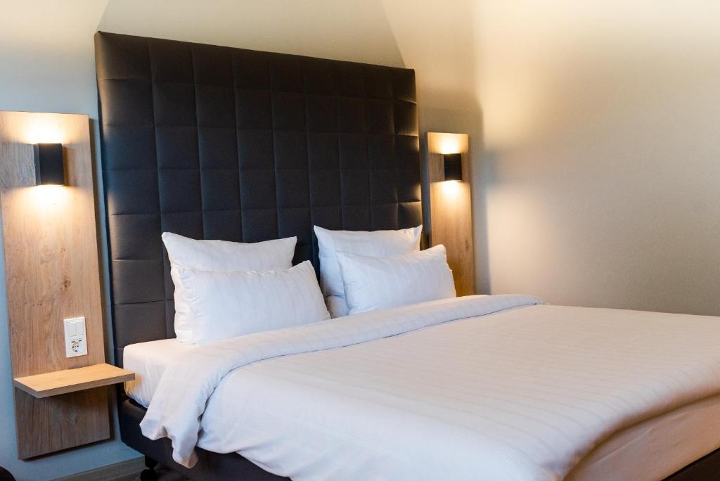 拉姆斯泰因-米森巴赫圆环酒店的一间卧室配有一张白色大床和黑色床头板