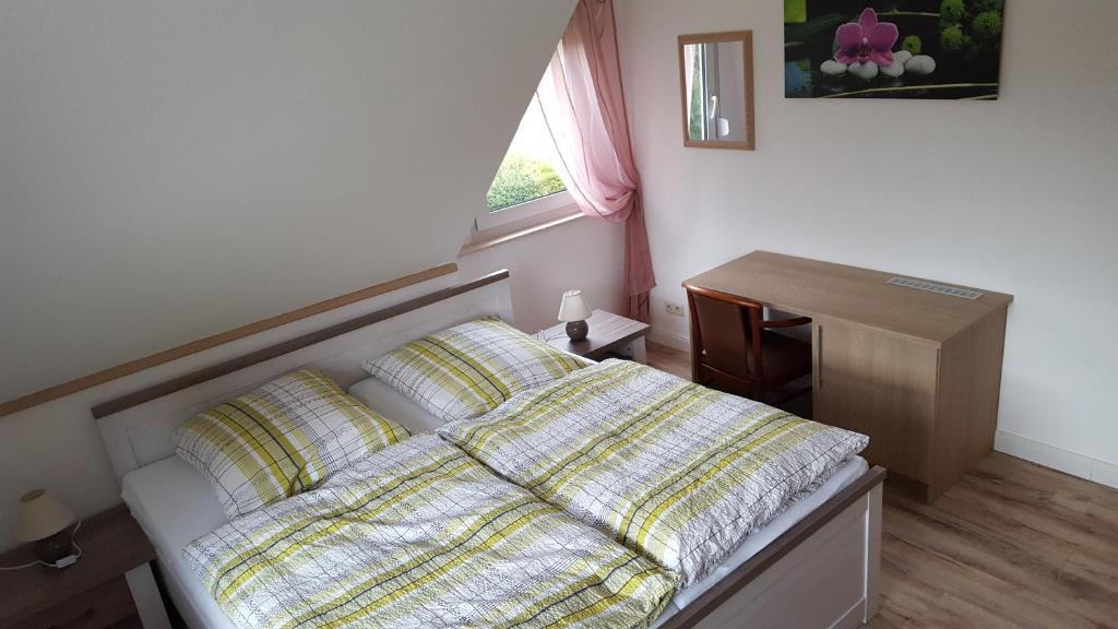 甘德尔克塞Gästehaus Strudthoff的一间卧室配有一张床、一张书桌和一个窗户。