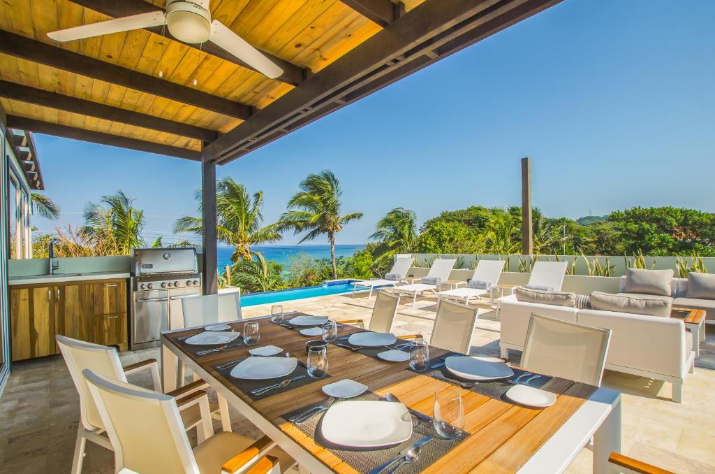 西湾Villa Topaz Above West Bay with 360 Degree Views!的户外用餐室配有桌椅