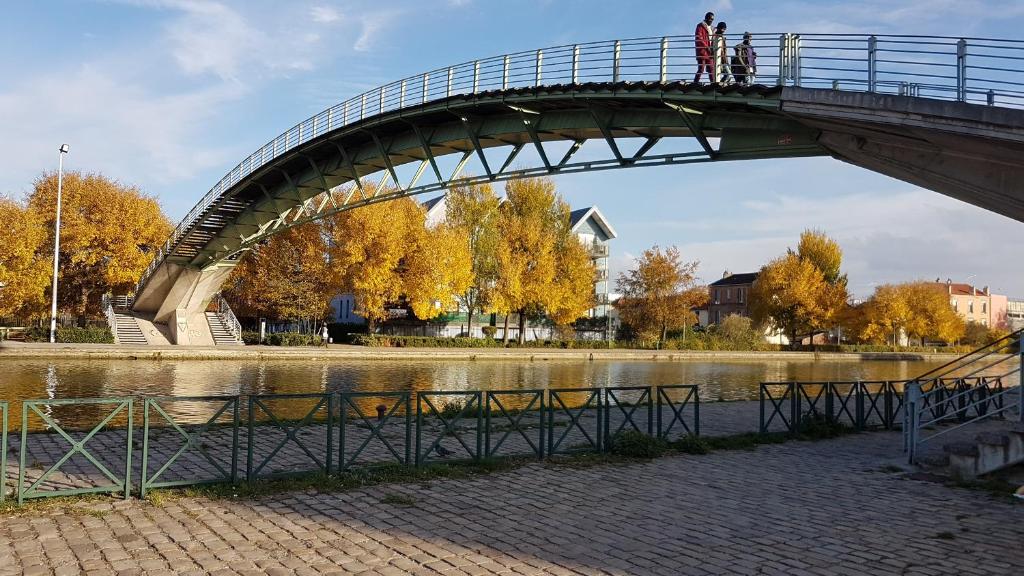 奥贝维利埃Chez Daniel, un 2 pièces proche de Paris STADE de FRANCE的一条河上的桥梁,人们在河上走