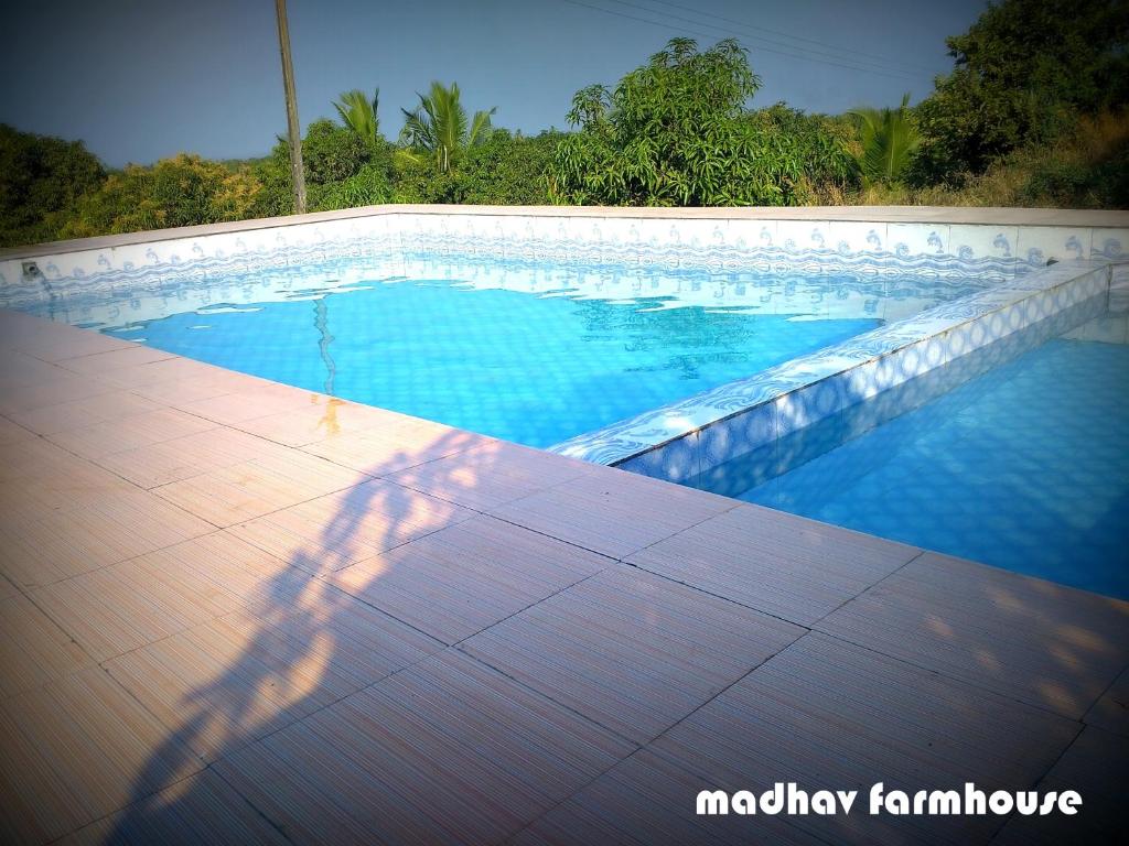 萨三吉尔Madhav Farmhouse的站在游泳池旁的人的影子