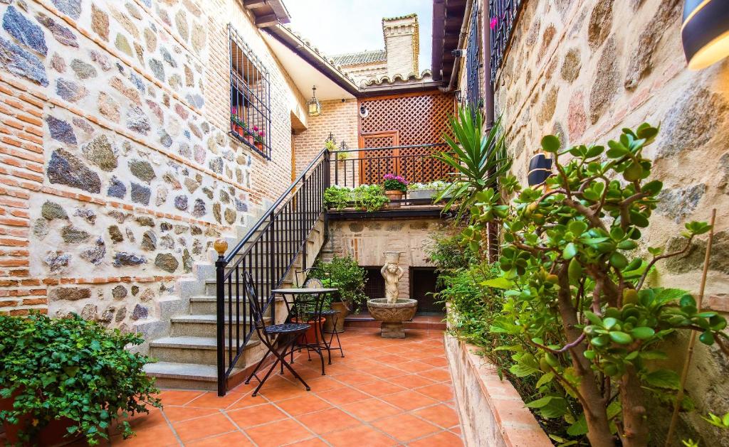 托莱多Casa de Bisagra的庭院设有楼梯和桌椅